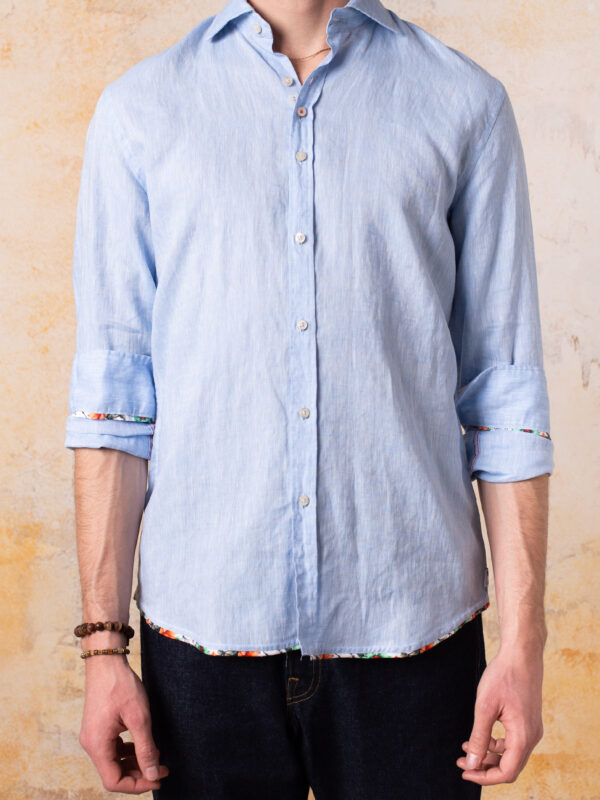 Camisa Bjovuit Formentera 02 Lino Azul Claro. Una camisa fresca y sofisticada, perfecta para los días cálidos, confeccionada en&nbsp;100% lino&nbsp;para brindar comodidad y estilo impecable. Tejido Lino 100%. Color azul claro. Tercer botón Bjovuit para un ajuste perfecto. Cuello campeón. Detalles en contraste tejido floral en el final de la camisa, el cuello y los puños. Camisa imprescindible y&nbsp;versátil. Fabricada y diseñada en Barcelona. Una prenda que fusiona frescura, estilo y los detalles exclusivos que definen a&nbsp;Bjovuit.